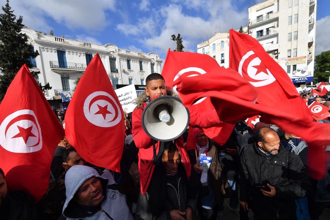 Tunisian demonstrators raise flags and protest placards as they take to the streets of the capital Tunis, on January 14, 2023, to protest against their president. FETHI BELAID/AFP VIA GETTY IMAGES